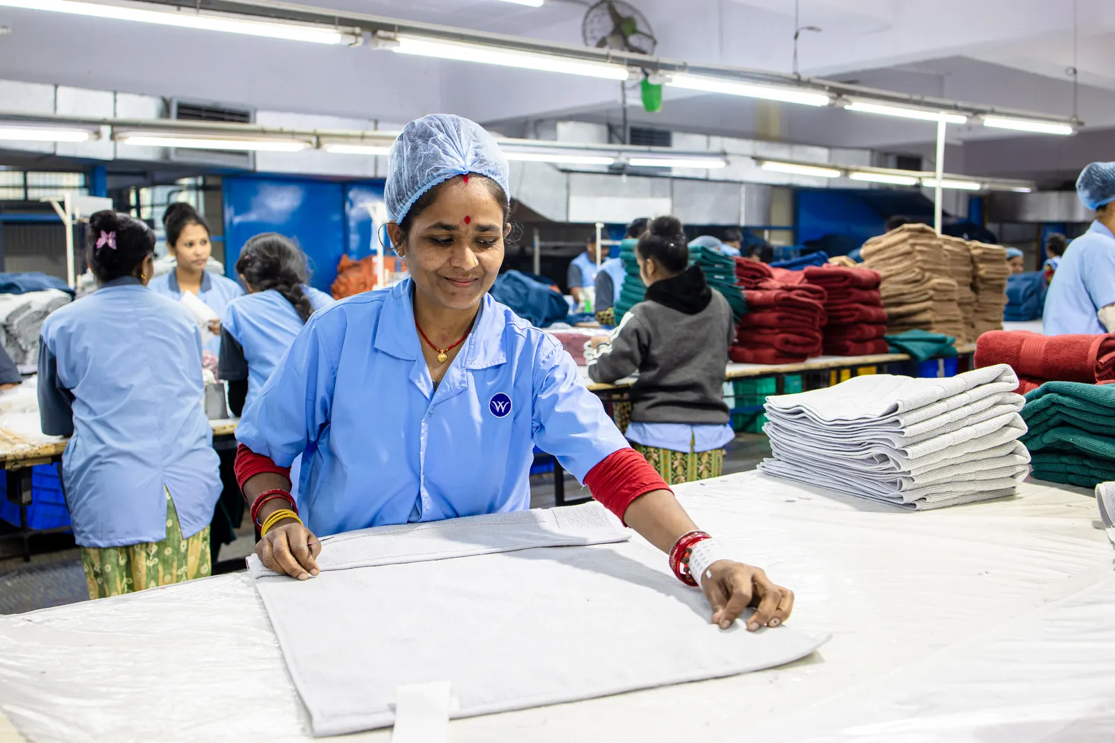 Production team in uniforms working along a finishing line in an Indian factory