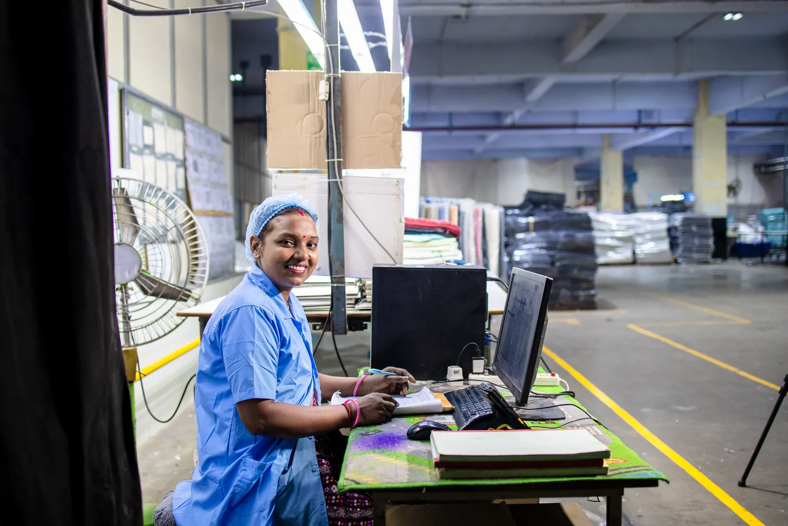Smiling factory worker in a blue uniform at her workstation in an Indian factory