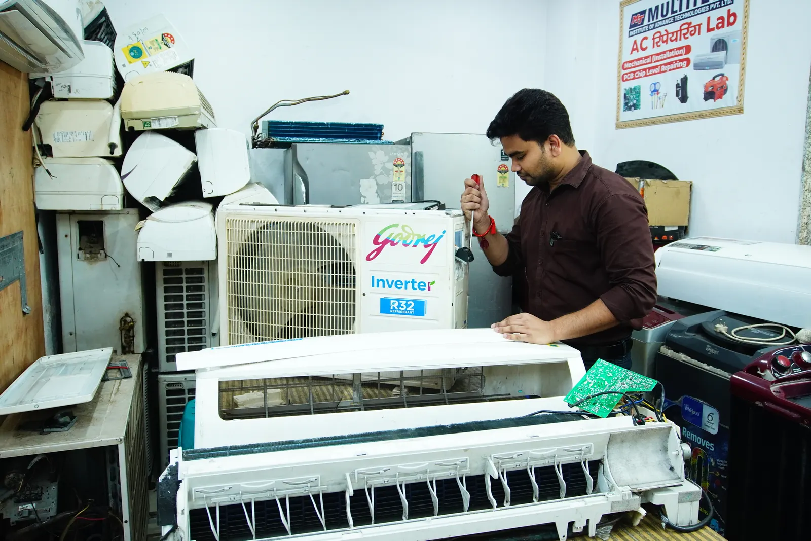Technician servicing an air-conditioning unit in a workshop in New Delhi